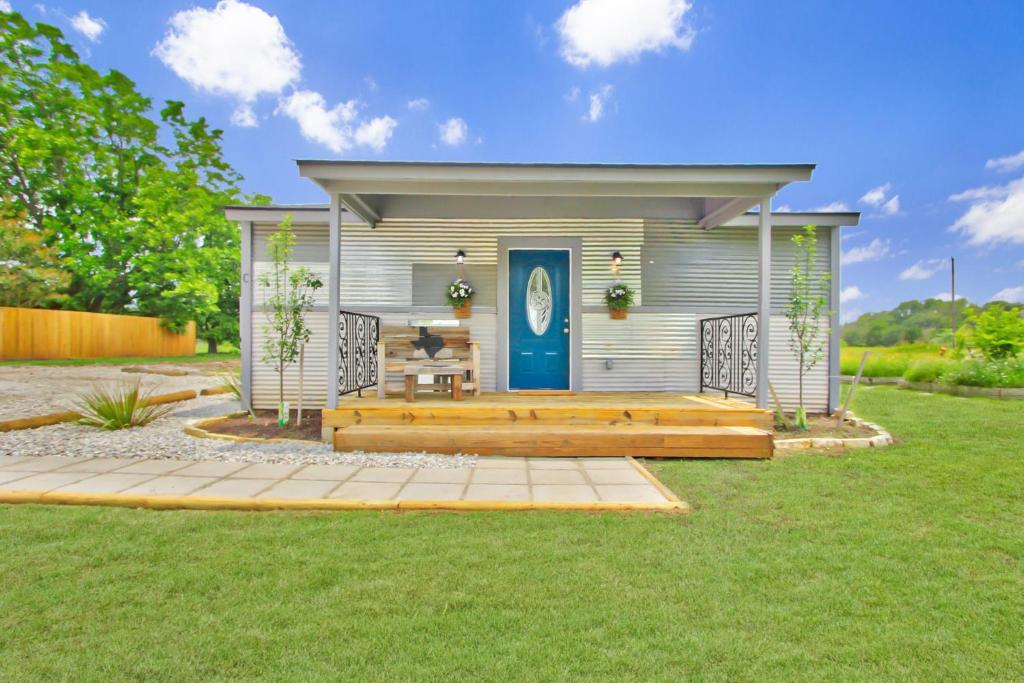 a tiny house with a blue door in a yard at Blue Jay Getaway in Blanco