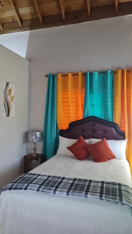 a bedroom with a bed with colorful curtains at Penthouse villa 1 in Montego Bay