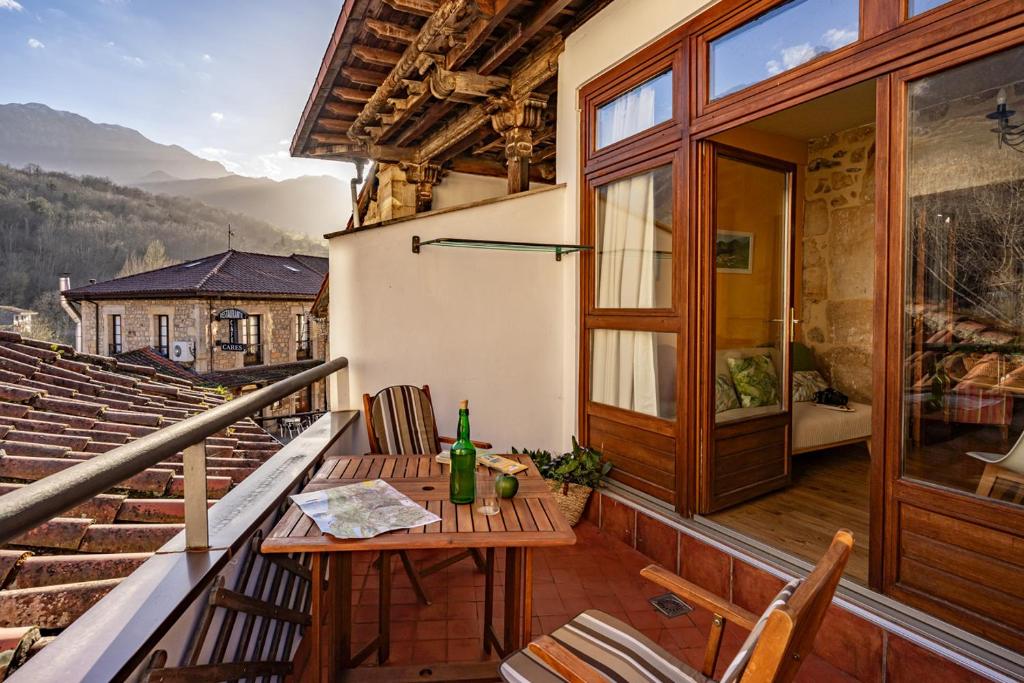 a balcony with a table and chairs and a glass door at Apto rurales y habitaciones MONTE CAORU - CABRALES apartahotel in Arenas de Cabrales
