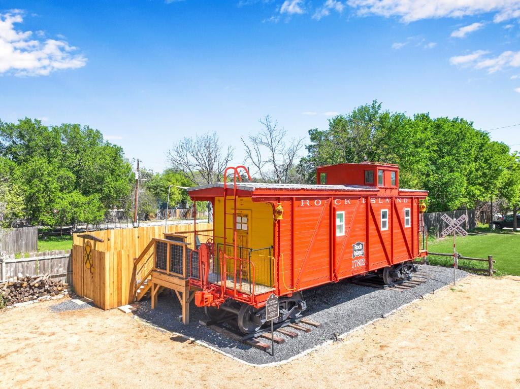 a red train car on display in a park at Caboose on the Square in Wimberley