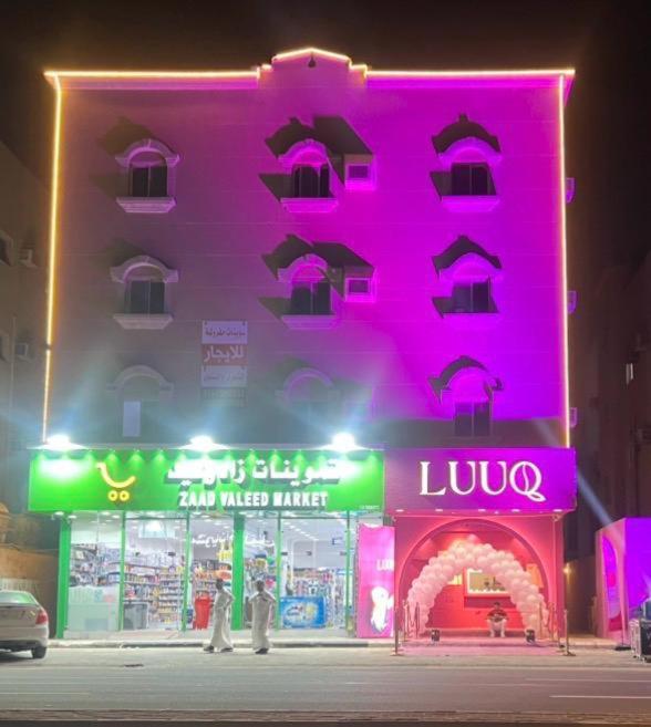 a pink building with a neon sign in front of it at سويتات مفروشة 2 in Al Hofuf