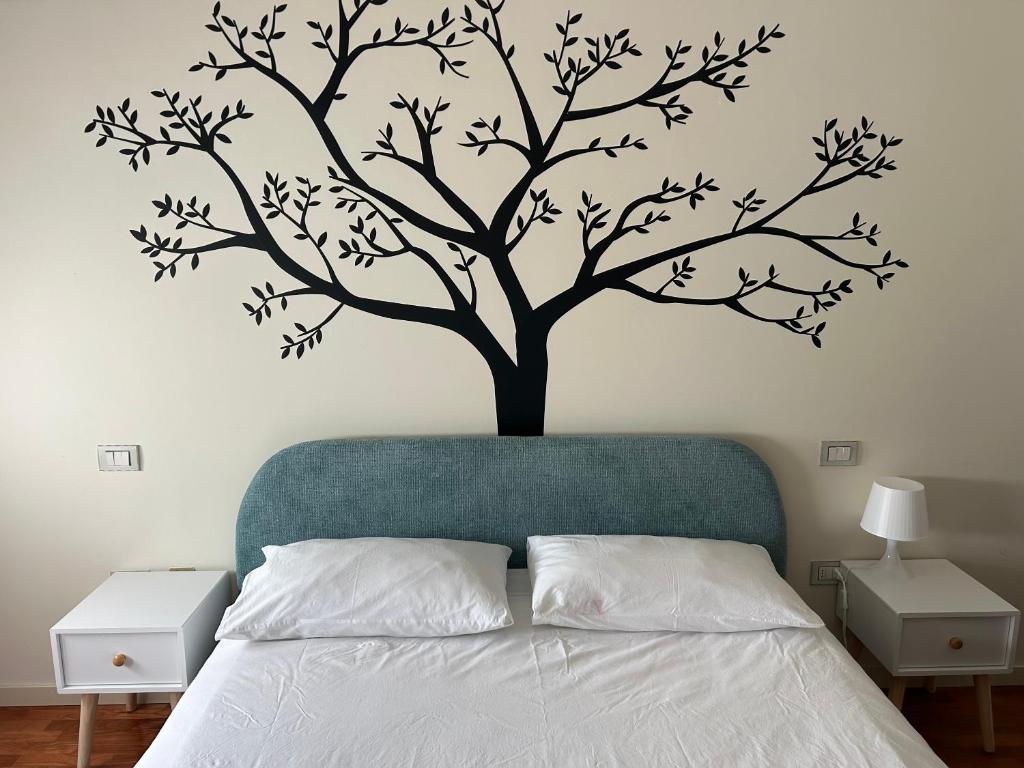 a tree stenciled on a wall above a bed at Casa Giulia in Santarcangelo di Romagna