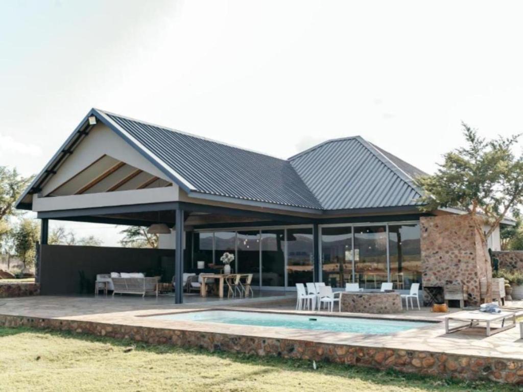 a pavilion with a pool and a patio at Stroomrivier Lodge in Boshoek