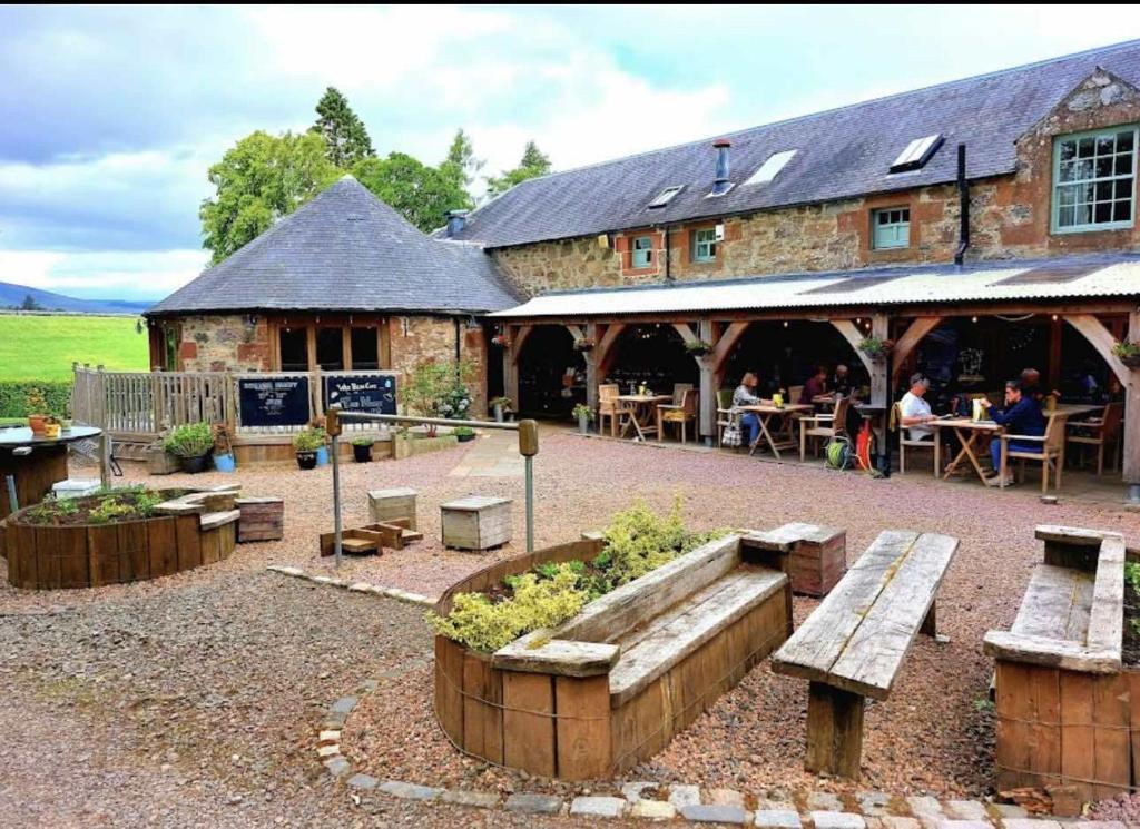 a building with benches and tables in front of it at Lodge at Lochside in Bridgend of Lintrathen