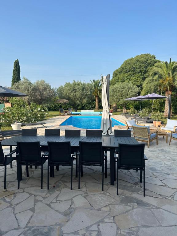 a table and chairs with an umbrella and a pool at Les Palmiers in Le Muy