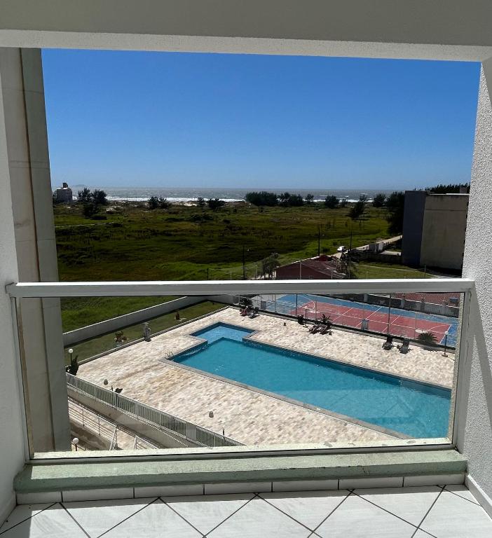 a view of a swimming pool from a window at Apartamento com vista imperdível in Laguna