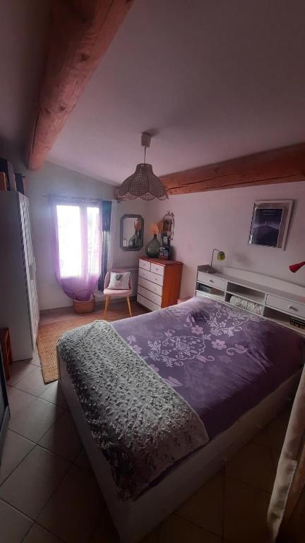 a bedroom with a large bed with a purple blanket at Chambre "Là Maison Haute" in Faucon