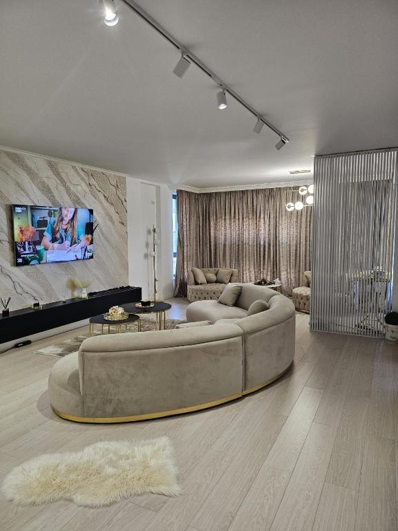 a living room with a large couch and a tv at Luxury Promenada Craiova in Craiova