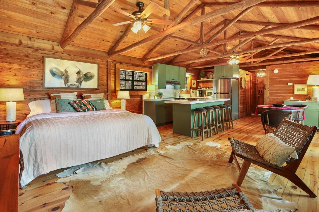 a bedroom in a log cabin with a bed and a kitchen at Lajitas at The Bend in Wimberley
