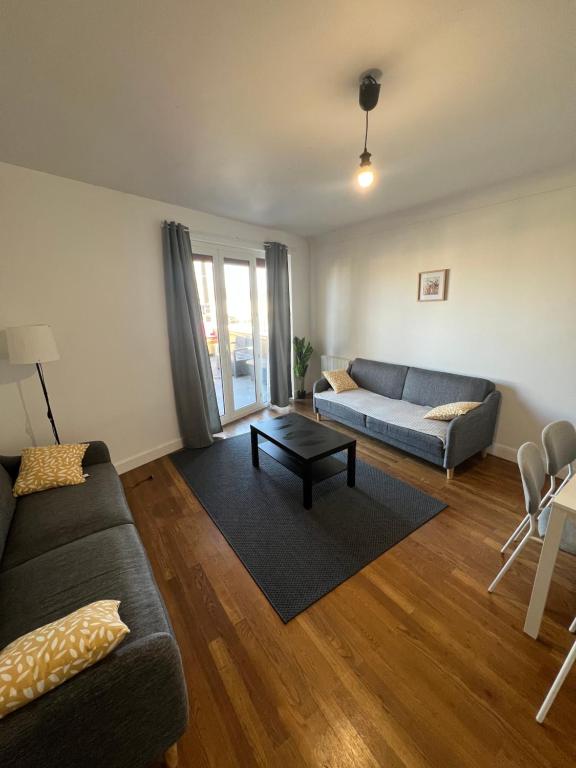 a living room with a couch and a table at Le Toit des Volcans - 8 couchages - Terrasse privée et Wifi in Clermont-Ferrand