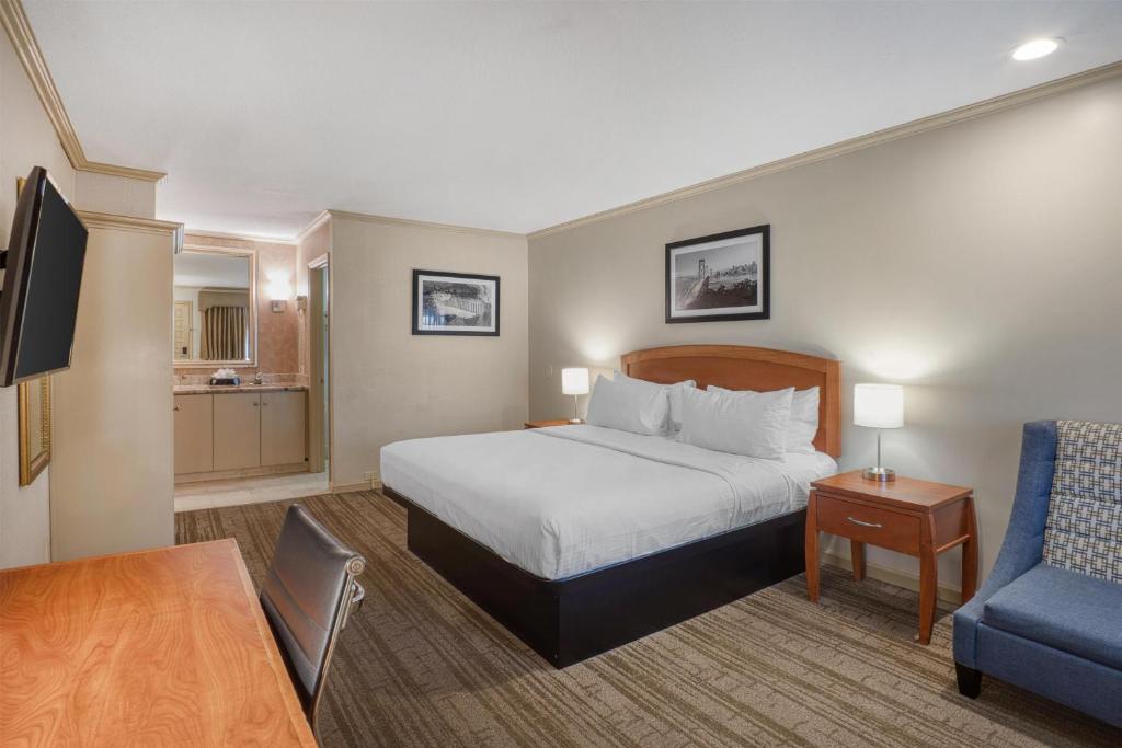 a hotel room with a bed and a blue chair at SureStay Plus Hotel by Best Western Mountain View in Mountain View