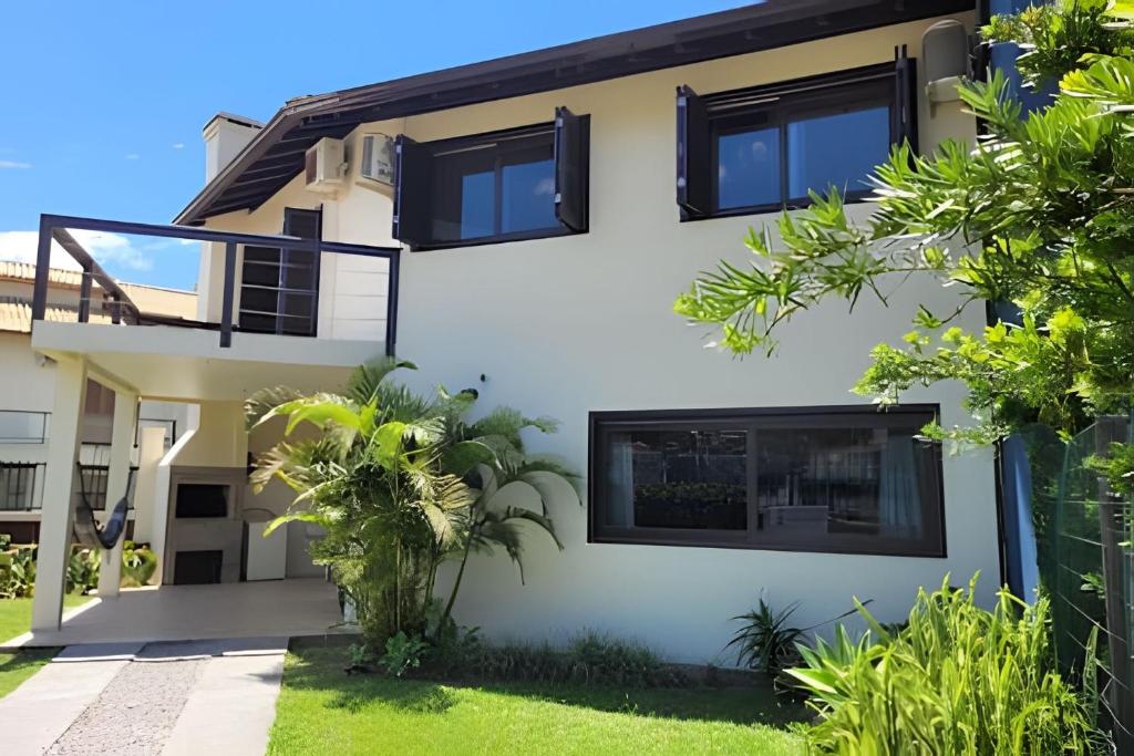 a house with black windows and green plants at Casa Morrinhos 01 in Garopaba