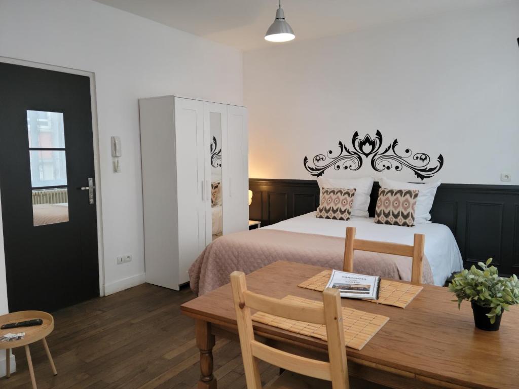 una camera da letto con un letto con un tavolo di legno e una sala da pranzo di Studio 1 du Temple Hyper Centre a Cambrai