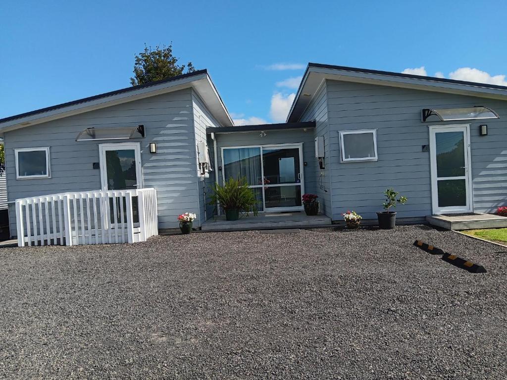 a gray house with a white fence and a driveway at Trailblazer Studios in Waihi