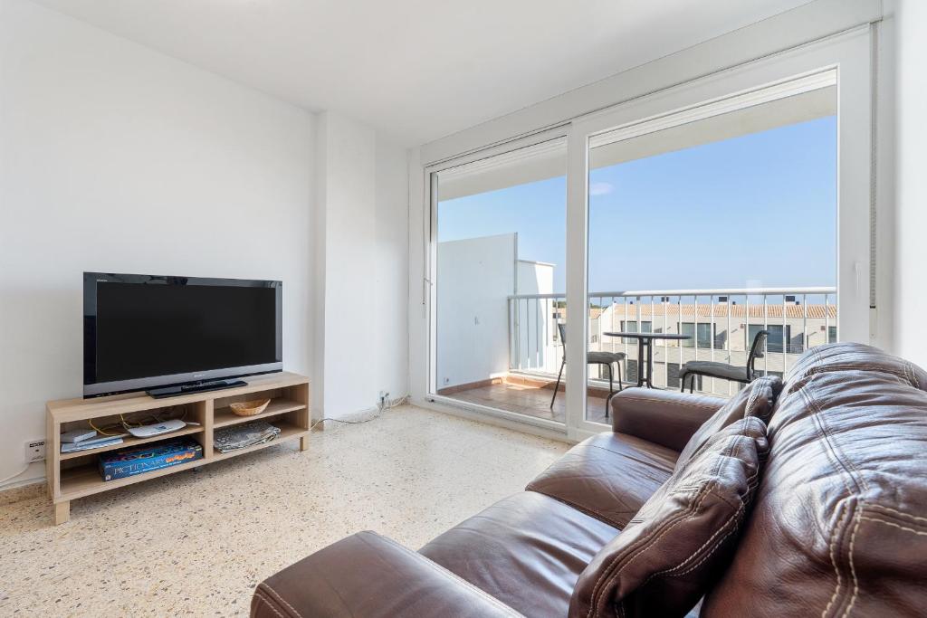a living room with a couch and a flat screen tv at Hauzify I Apartament Esmeralda in L'Ametlla de Mar