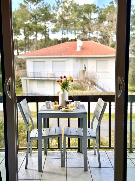 a table and chairs on a balcony with a view of a house at Studio Cosy in Mimizan-Plage
