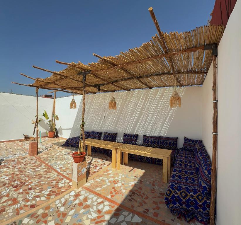a patio with a wooden bench under a roof at Blue Tizirin House in Tamraght Ouzdar