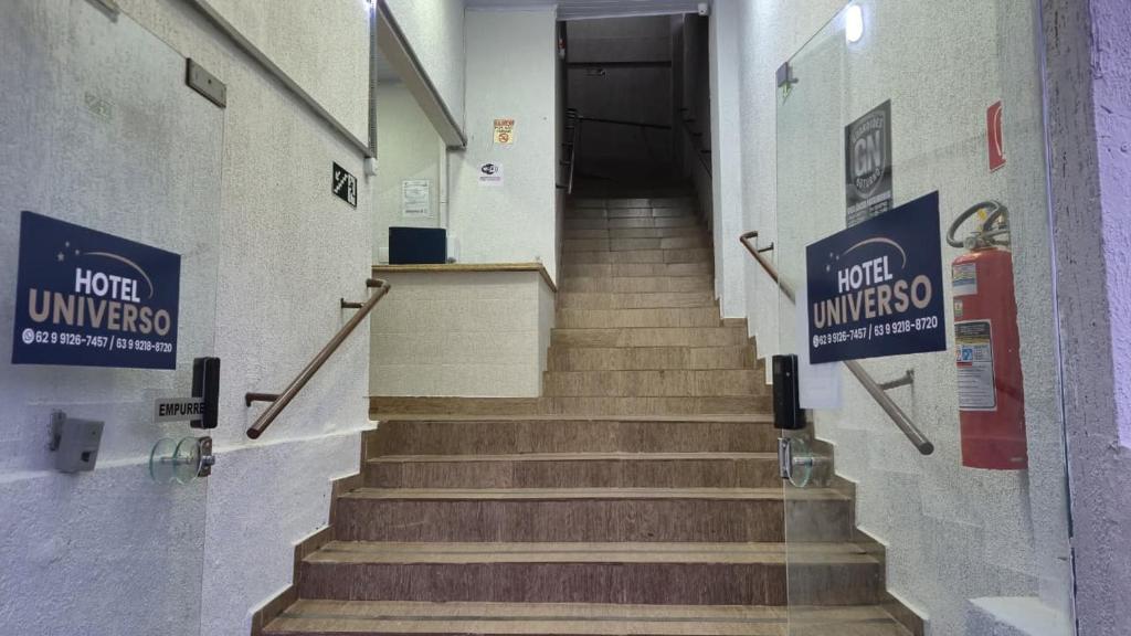 a hallway with stairs in a building with signs on the wall at Hotel Universo in Goiânia