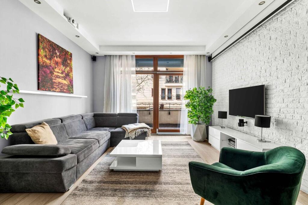 a living room with a couch and a tv at Wilanów Cinema Apartment in Warsaw