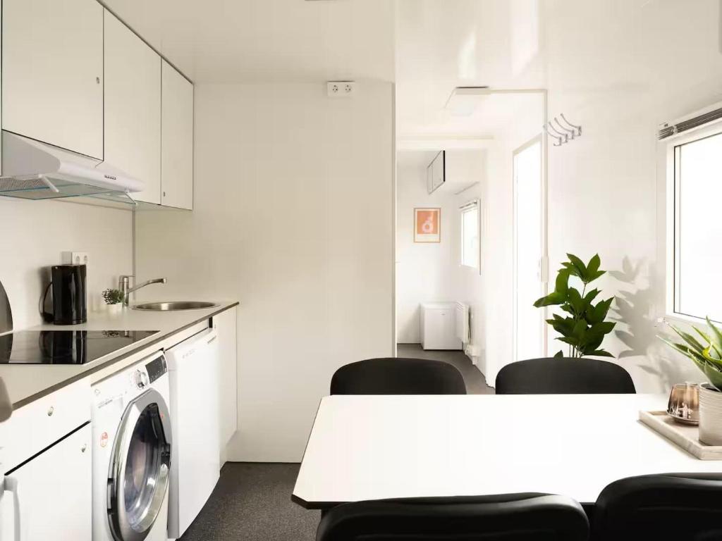 a white kitchen with a washing machine and a table at Budget Mobile House in Faroe Islands in Strendur