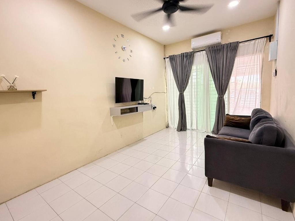 a living room with a couch and a clock on the wall at Qisa Guesthouse 03 in Arau