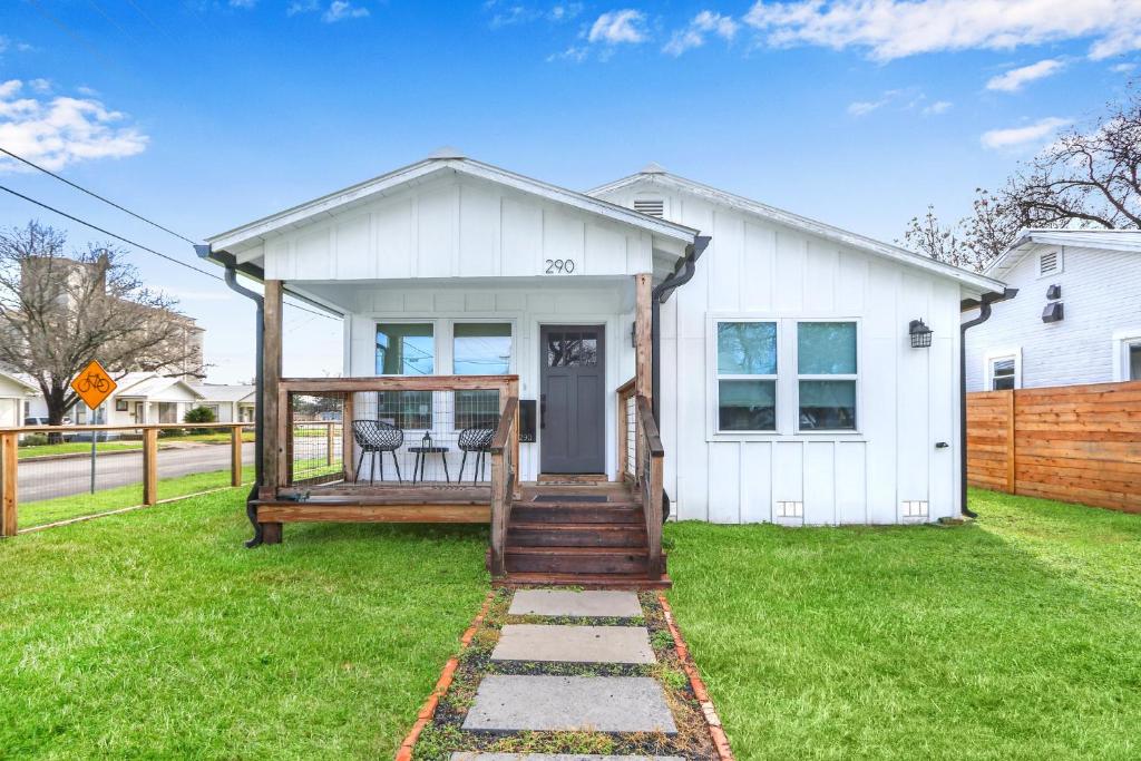 a white house with a porch with two chairs at Bridge Haus in New Braunfels