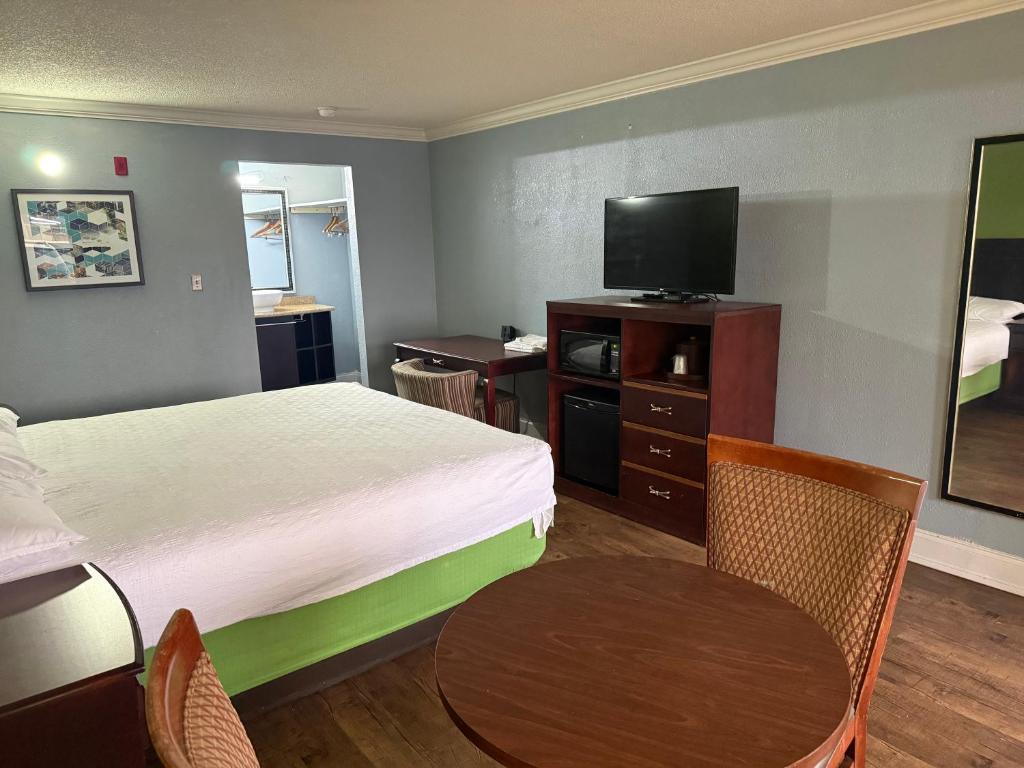 a hotel room with a bed and a table and a television at Soho inn & suites in Perry