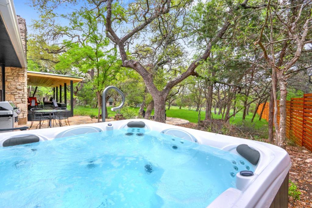 a jacuzzi tub in a yard with trees at Red Bird Cottage in Wimberley