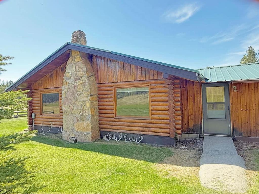 a log cabin with a door and a grass yard at 12 Mile Ranch in Custer