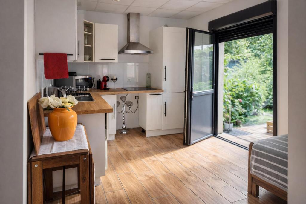 a kitchen with white cabinets and a large sliding glass door at Channel-Appartement cosy avec piscine, jardin & nature aux portes de Paris in Saint-Maurice