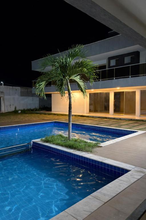 a palm tree in a swimming pool in front of a building at Green House in Juazeiro do Norte