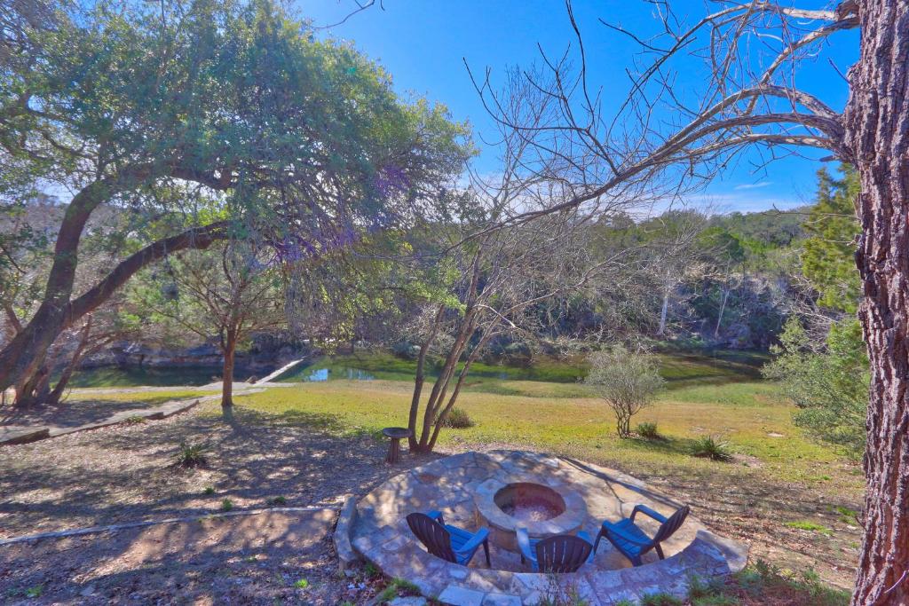 a stone fire pit in a park with trees at Clearwater Log Home in Wimberley
