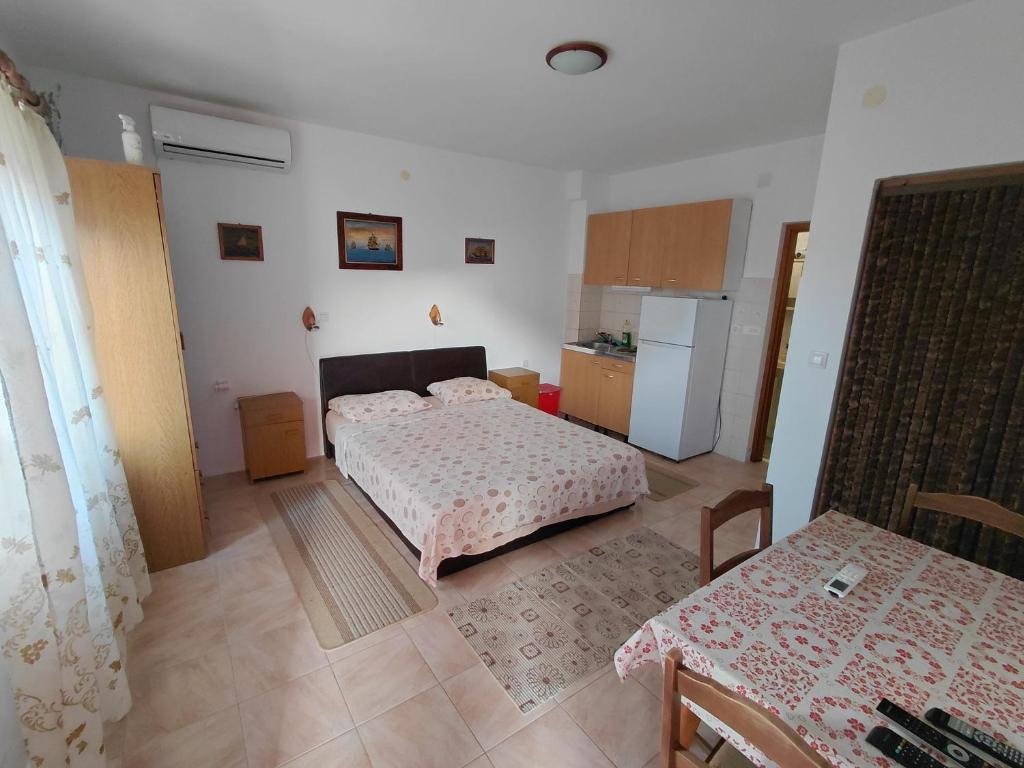 a bedroom with two beds and a kitchen with a refrigerator at Kuća za odmor STIPE in Pag