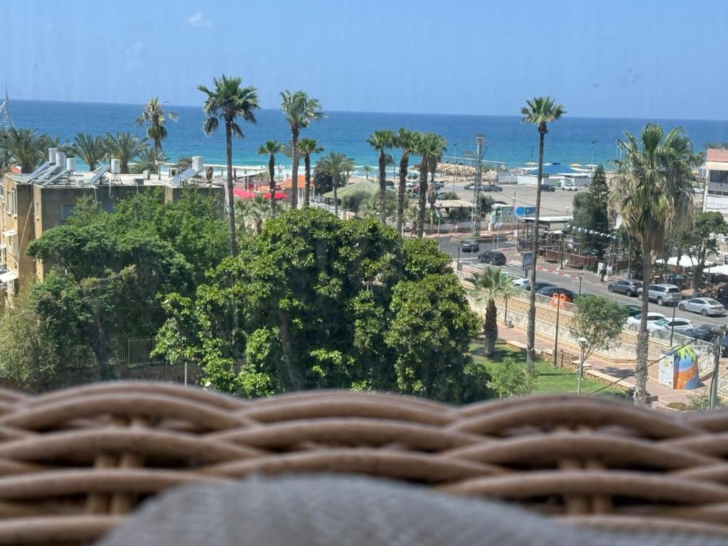 a view of the beach and palm trees from a balcony at Sea180 in Nahariyya