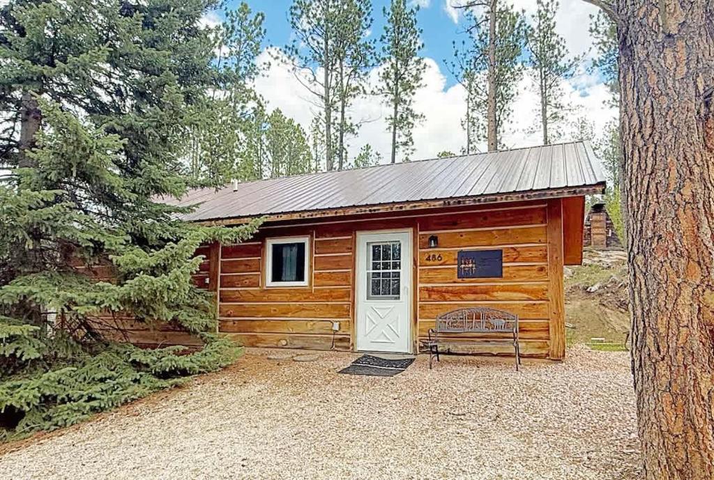 a log cabin with a white door and a bench at Schuster's Cabin in Custer