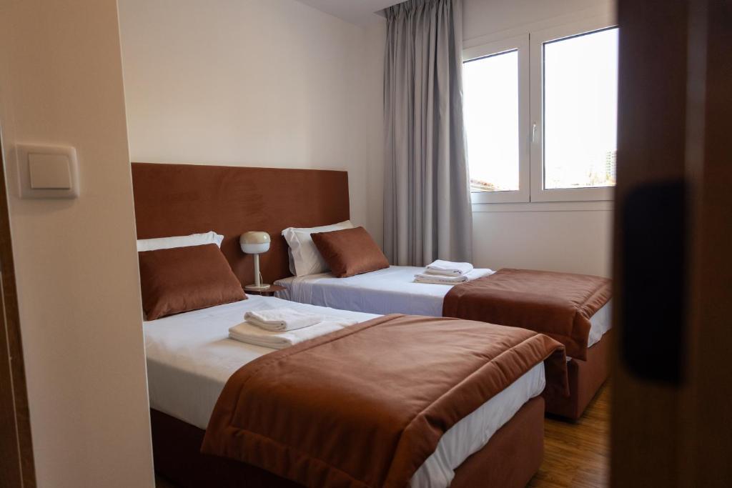 a hotel room with two beds and a window at Trio Living Residences in Vila Real
