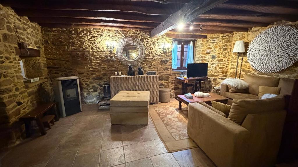 a living room with a couch and a stone wall at Rego de Cora By Oktheway in Valcarría