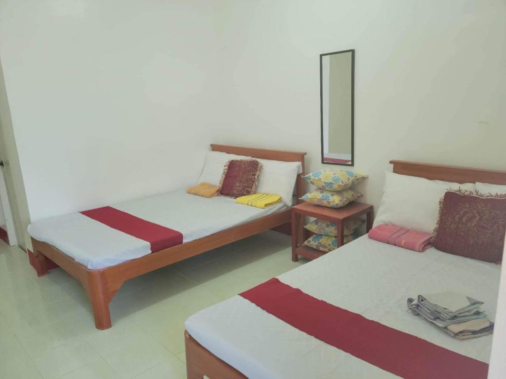 a room with two beds and a mirror at Mamita Seaside Resort in Guinisiliban