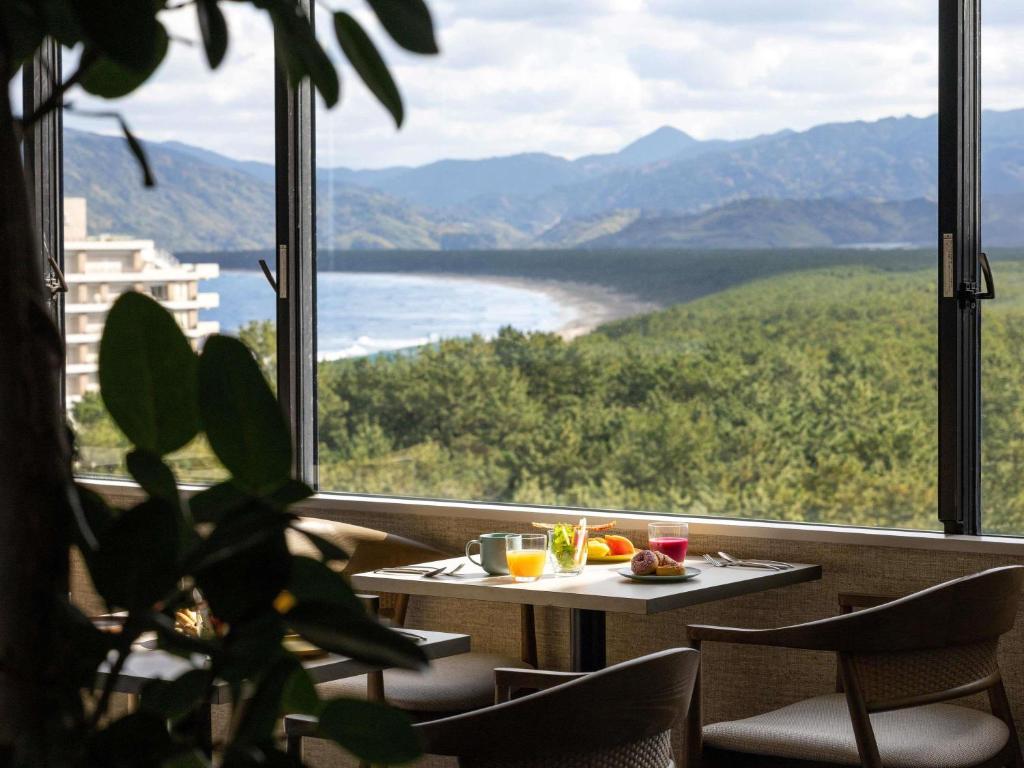 a table and chairs in front of a large window at Mercure Saga Karatsu Resort in Karatsu