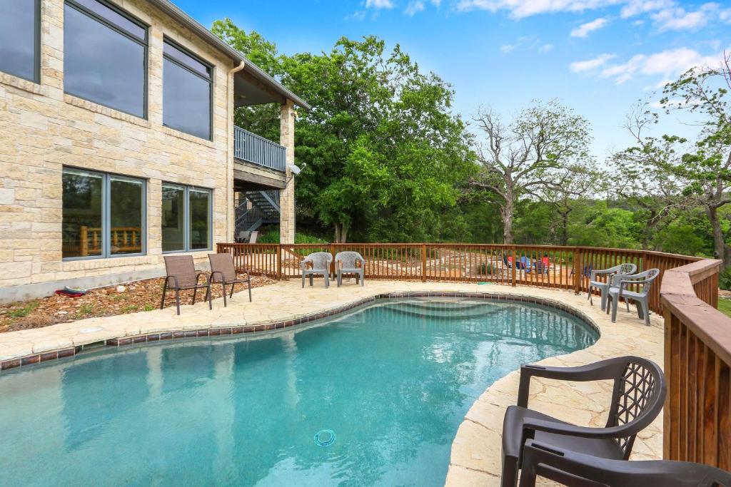 a swimming pool with chairs and a house at Rio Cantando in Wimberley