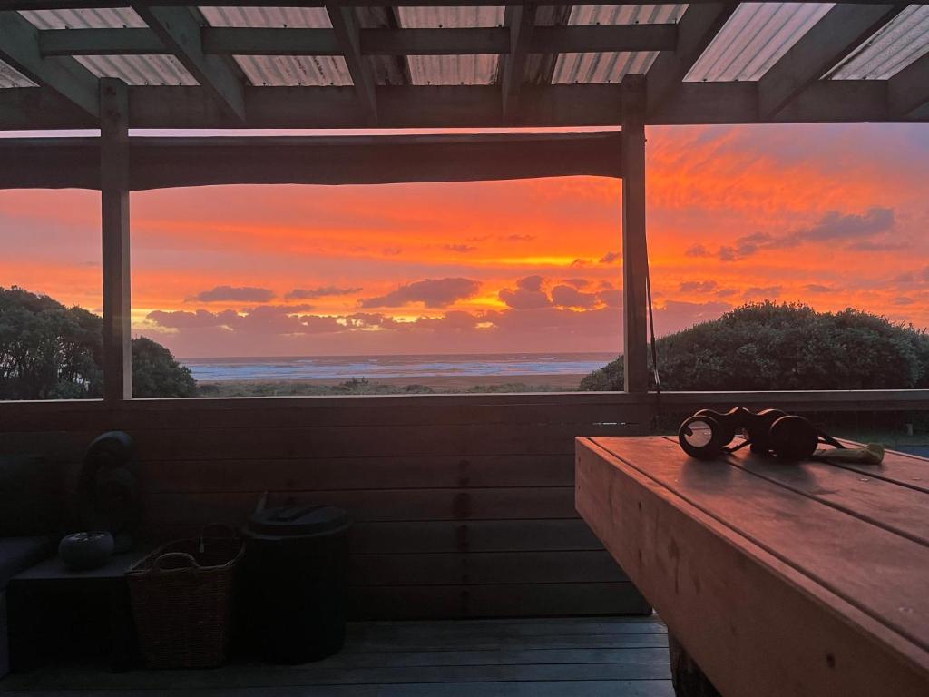 a pair ofoculars sitting on a table in front of a sunset at Beachfront Sunset Bach in Piha