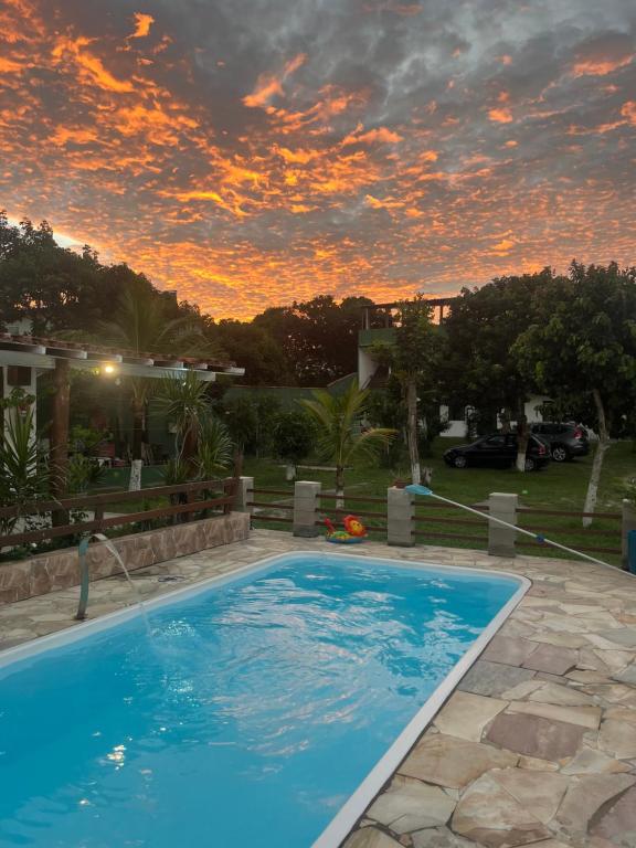 a swimming pool in a yard with a sunset at Pousada Vale Do Aijalom in Cabo Frio