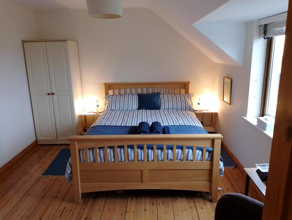 a bedroom with a bed with blue sheets and two lamps at Ardnacassa in Kilcrohane