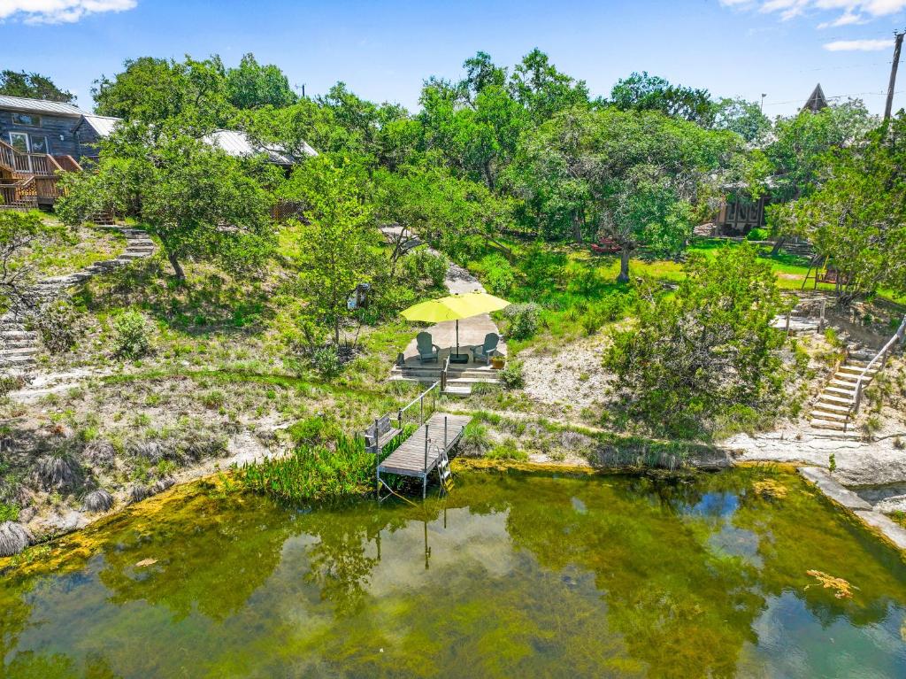 an overhead view of a pond with a bench and an umbrella at Creekside Vista Escape - Cabin in Wimberley