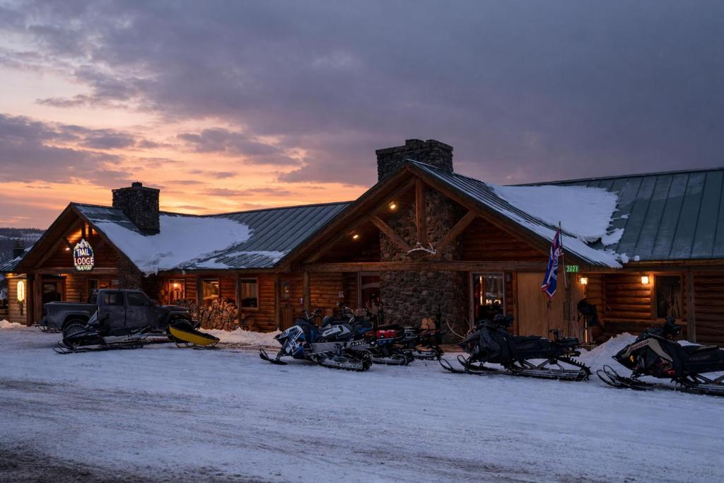 a log cabin with snow on the roof and motorcycles parked outside at Lava Mountain Lodge in Dubois