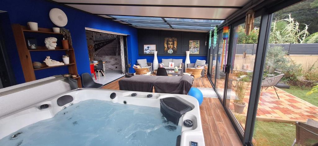 a bath tub in a room with a large window at A L'OMBRE DES 2 TILLEULS maison d'hôtes adults only in Sainte-Pazanne