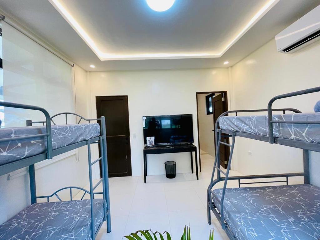 a room with three bunk beds and a flat screen tv at Camp J Staycation in Cayucay
