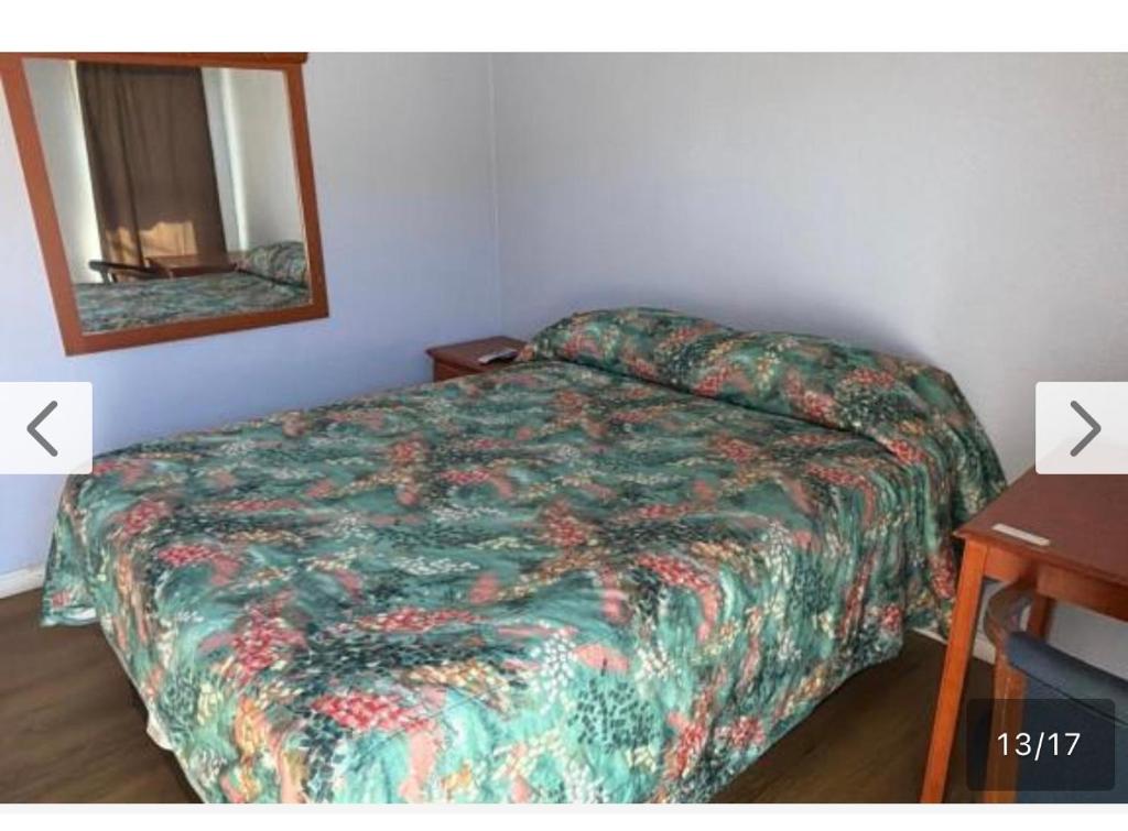 a bedroom with a bed and a mirror and a table at El Muir Motel in Fresno