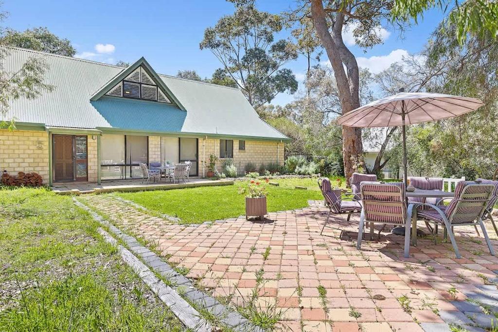 a patio with chairs and an umbrella in front of a house at Eagle Bay Beach Lodge - Escape to Coastal Serenity in Dunsborough