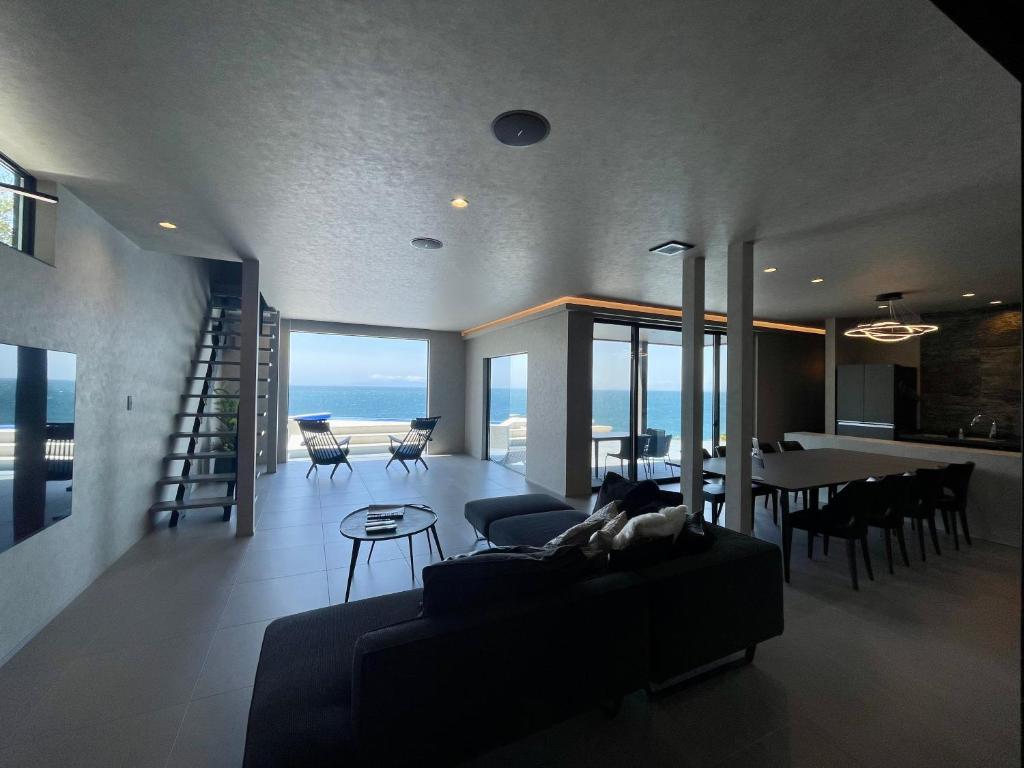 a living room with a couch and a table with chairs at eureka awaji 絶景インフィニティプール x 露天温水ジャグジー付きヴィラ in Sumoto